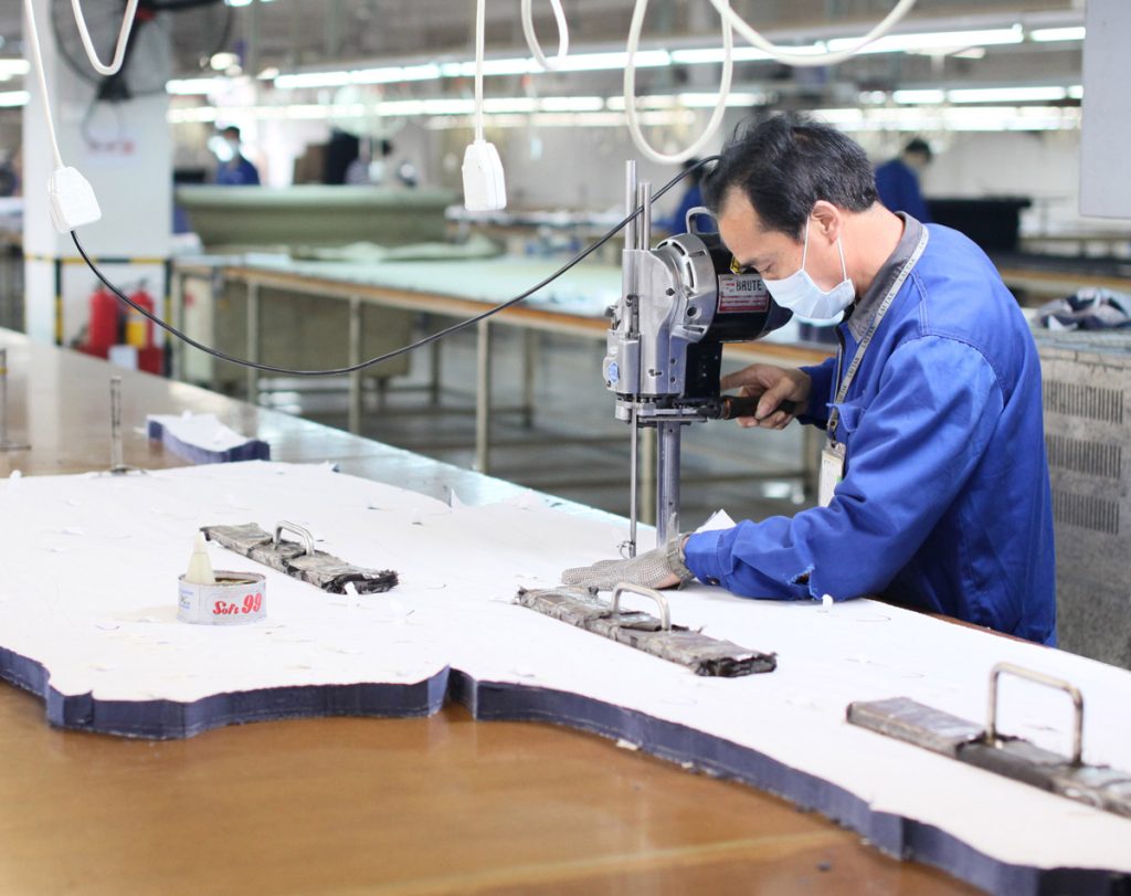 Worker cutting stacked fabric with an electric cutting machine