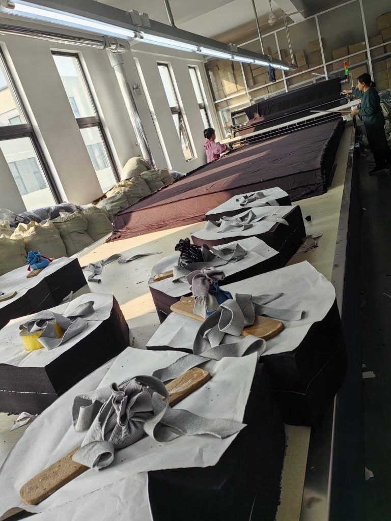 Fabric cutting table with layered textile and garment pattern pieces