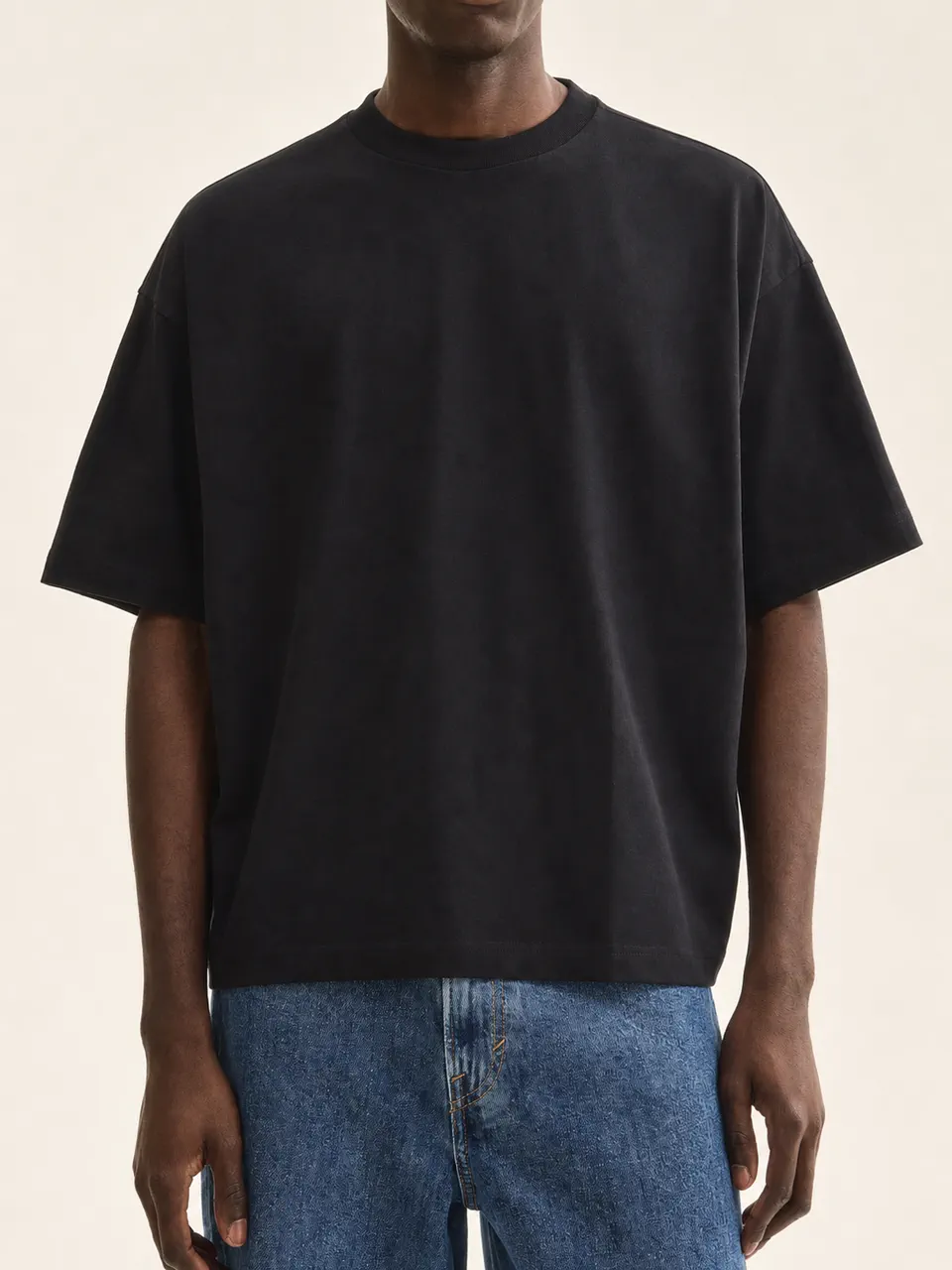 男性モデル着用の黒いボックスシルエット・オーバーサイズTシャツ。OEMストリートウェアの参考