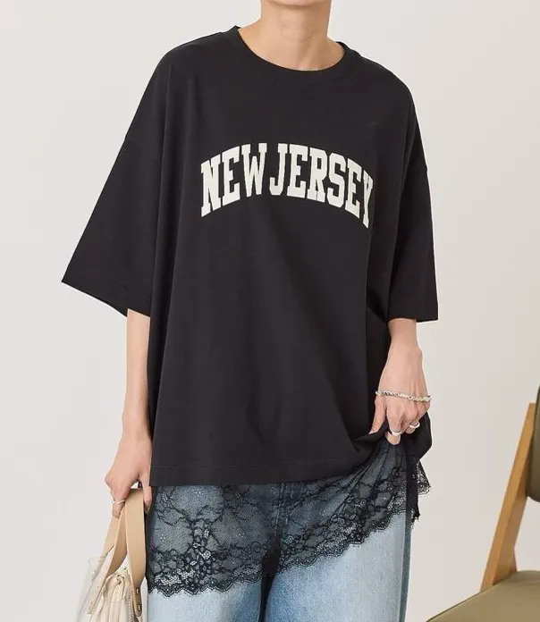 裾にレースをあしらった黒のオーバーサイズグラフィックTシャツ。カジュアルウェアのブランド別注参考