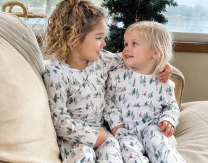 Two children in matching tree-print pajamas for seasonal family matching sleepwear program planning