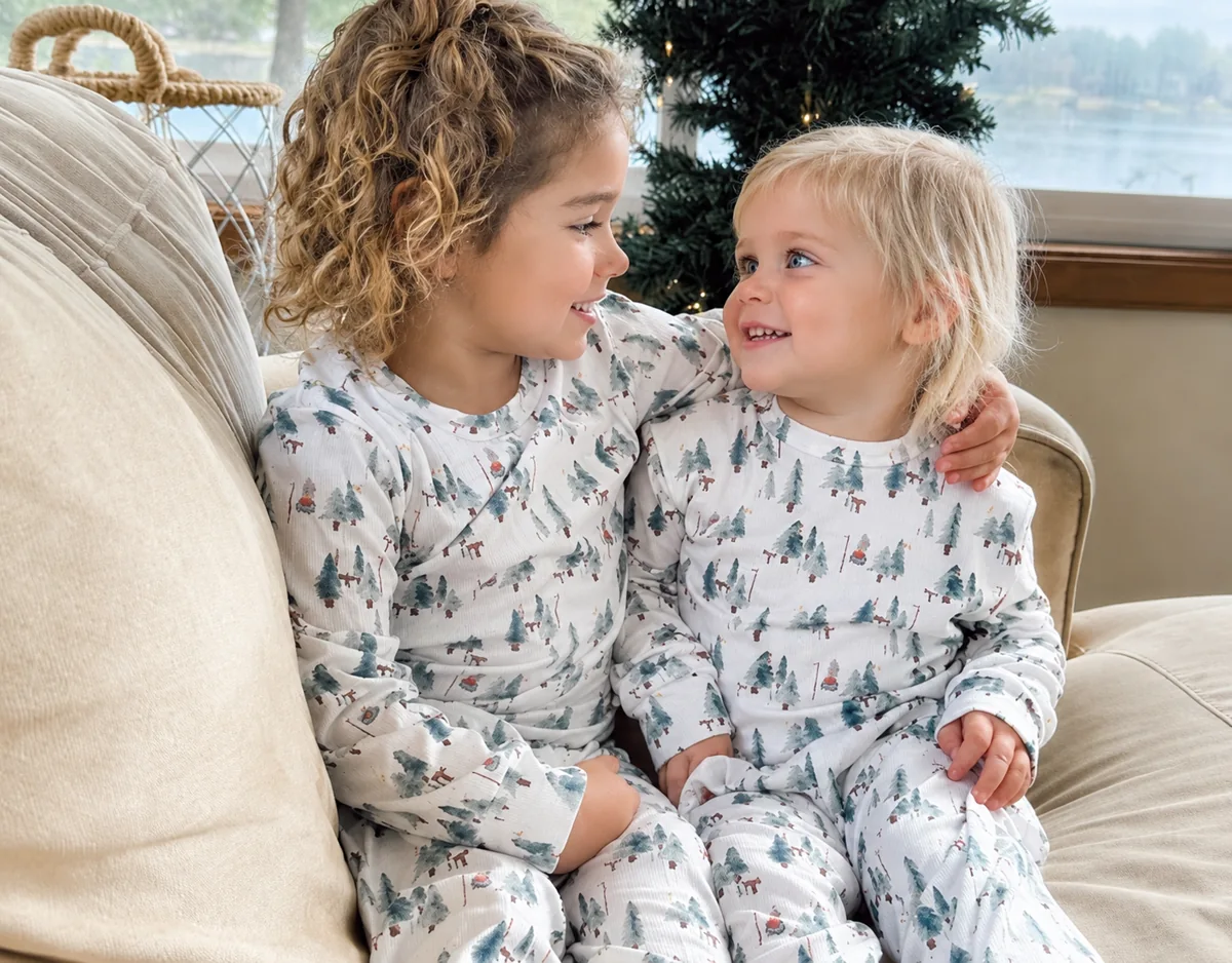 Two children in matching tree-print pajamas for seasonal family matching sleepwear program planning