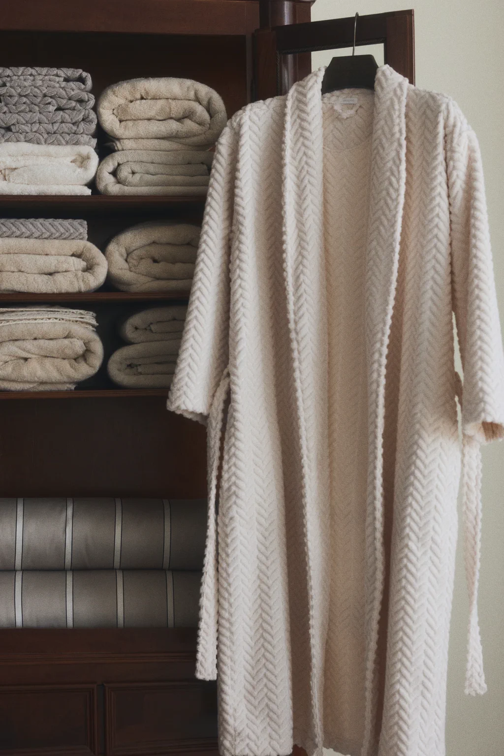 Textured white robe hanging beside folded towels for sleepwear quality control and robe finishing review